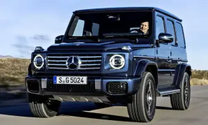 Ciemnoniebieski Mercedes G Klasa w ruchu. Kierowca uśmiecha się. Sprawdź aktualną mercedes g klasa cena.