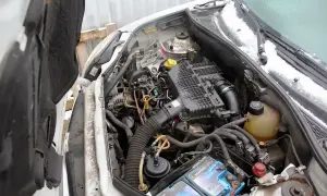 Silnik Renault Kangoo 1.5 dCi, widok komory silnika z otwartą maską. Widać akumulator, filtry i przewody.