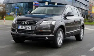 Ciemny Audi Q7 3.0 TDI w ruchu miejskim, z widocznym polskim numerem rejestracyjnym PO 2896X.