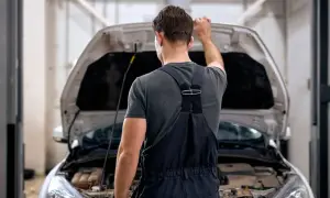 Mechanik zamyka maskę samochodu. Zastanawia się, ile czasu stygnie silnik, zanim będzie mógł kontynuować pracę.