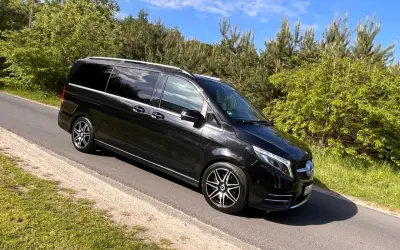 Czarny Mercedes-Benz V-klasa na drodze wśród zieleni.