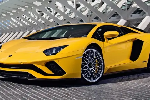 Żółty Lamborghini Aventador z futurystyczną architekturą w tle.