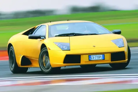 Żółty Lamborghini Murcielago pędzi po torze wyścigowym, zostawiając za sobą rozmyte zielone krajobrazy.