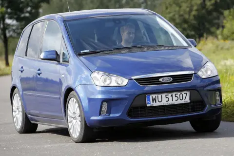 Niebieski Ford C-Max 1.6 benzyna z mężczyzną za kierownicą jedzie po drodze wśród zieleni.