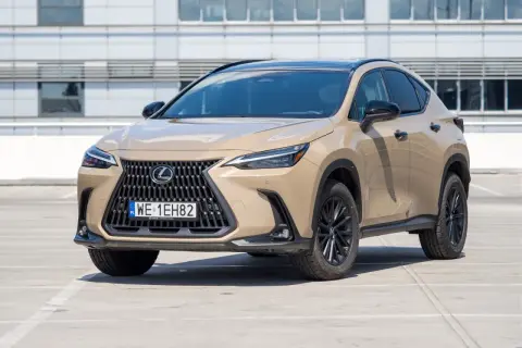 Elegancki, beżowy Lexus 350h z czarnym dachem i felgami stoi na parkingu przed nowoczesnym budynkiem.