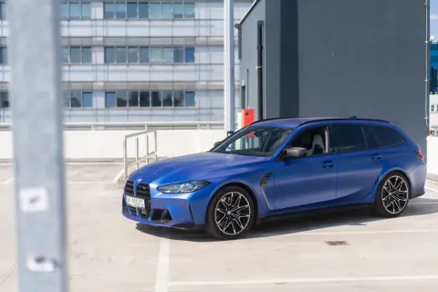 Niebieskie BMW M3 Touring na parkingu. Sportowy kombi z charakterystycznymi felgami i matowym lakierem.