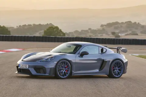 Szary Porsche GT4 RS na torze wyścigowym, z charakterystycznym skrzydłem i niebieskimi felgami.
