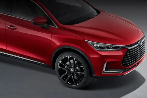 Czerwony BYD Tang błyszczy na ciemnym tle, prezentując eleganckie linie i sportowe felgi.