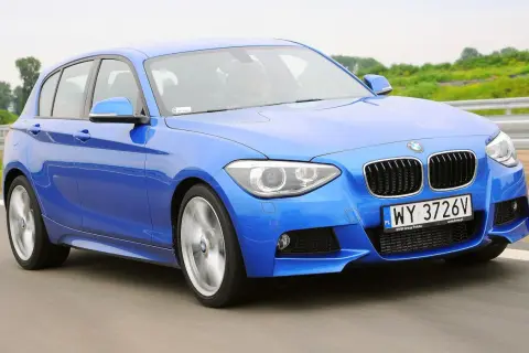 Niebieskie BMW 116i pędzi po drodze, ukazując swoje sportowe linie i dynamiczny charakter.