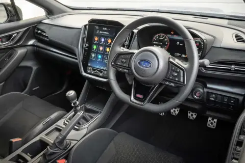 Wnętrze Subaru STI z dużym ekranem dotykowym, cyfrowymi zegarami i sportową kierownicą. Gotowy na jazdę!