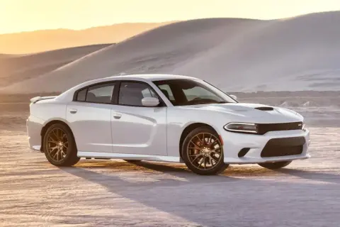 Biały Dodge Charger SRT z brązowymi felgami na pustyni o zachodzie słońca.