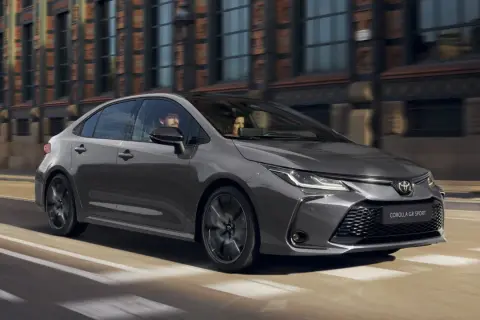 Szara Toyota Corolla GR Sport jedzie ulicą miasta. W środku siedzi para.