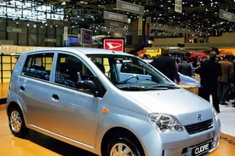 Srebrny Daihatsu Cuore na targach motoryzacyjnych, wśród tłumu ludzi i innych stoisk.