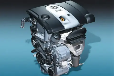 Silnik samochodowy 1.6 MPI z widocznymi paskami, alternatorem i osłoną z logo VW.