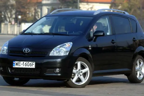 Czarna Toyota Corolla Verso z relingami dachowymi, zaparkowana na ulicy.