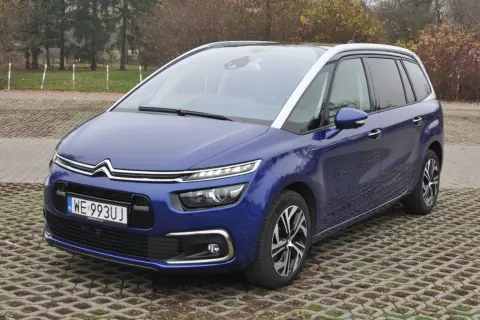 Niebieski Citroen C4 Spacetourer zaparkowany na betonowej nawierzchni z trawą.