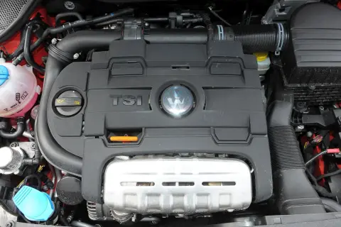 Silnik TSI w Volkswagen Polo 6R. Widoczny czarny plastikowy dekiel z logo VW i napisem TSI, a pod nim metalowa osłona.