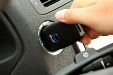 Dłoń wkłada kluczyk do stacyjki. To pokazuje, jak działa immobilizer, zabezpieczając auto przed kradzieżą.