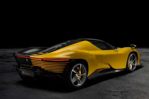 Żółty Ferrari Daytona z czarnym dachem i detalami, prezentujący swoje sportowe linie na ciemnym tle.