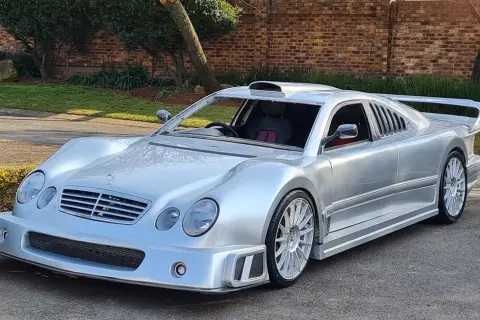 Srebrny Mercedes CLK GTR z masywnym spojlerem i wlotem powietrza na dachu, gotowy do wyścigu.