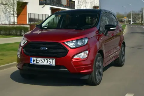 Czerwony Ford Ecosport z czarnym dachem jedzie po miejskiej drodze.