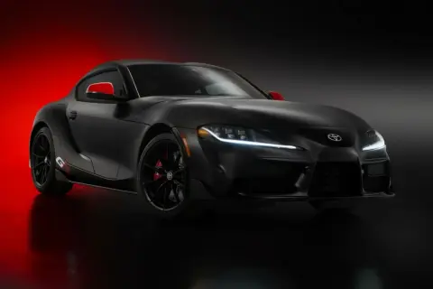 Czarna Toyota Supra GR z czerwonymi akcentami na lusterkach i zaciskach hamulcowych, prezentująca sportowy design.