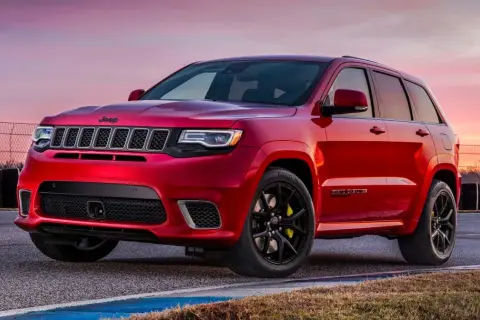 Czerwony Jeep Grand Cherokee Trackhawk na torze wyścigowym, gotowy do akcji.