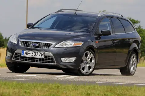 Ciemnoszary Ford Mondeo MK4 2.0 TDCI na drodze, z widocznym polem zboża w tle.