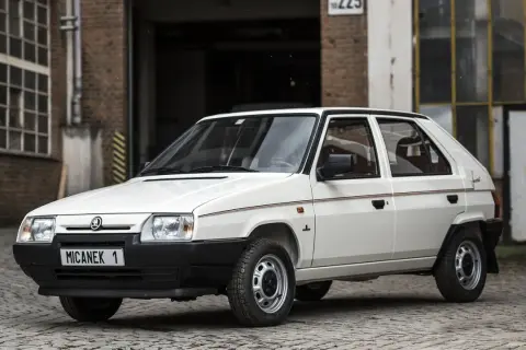 Biały Skoda Favorit z lat 90. na tle ceglanego budynku.
