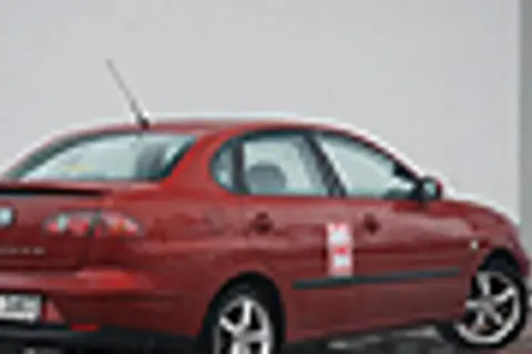 Czerwony Seat Cordoba z naklejką na drzwiach, zaparkowany na zewnątrz.