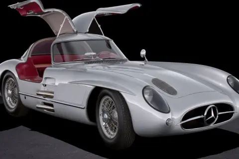 Srebrny Mercedes 300 SL Gullwing z otwartymi drzwiami, czerwone wnętrze, klasyk motoryzacji.