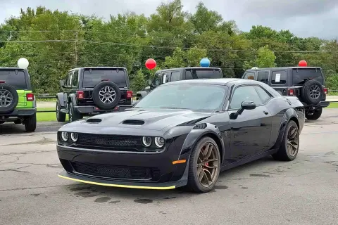 Czarny Dodge Challenger SRT z żółtym akcentem na zderzaku. Obok inne samochody i balony. Sprawdź dodge challenger cena!