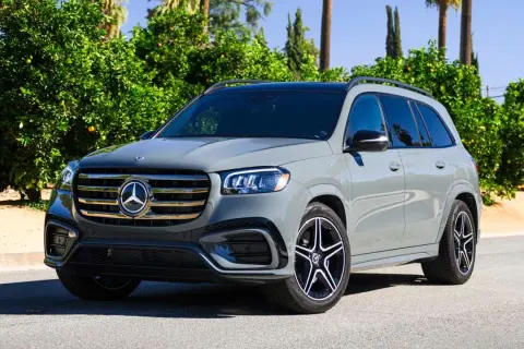 Szary Mercedes-Benz GLS na tle zieleni. Elegancki SUV z charakterystycznym grillem i felgami.