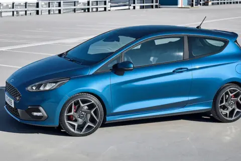 Niebieski Ford Fiesta ST z czarnym dachem i felgami stoi na parkingu.