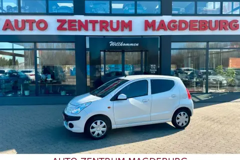 Biały Nissan Pixo zaparkowany przed salonem Auto Zentrum Magdeburg.