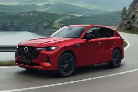 Czerwona Mazda CX-60 3.3 diesel pokonuje zakręt na malowniczej drodze.