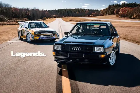 Dwa kultowe Audi quattro S1 na drodze. Jeden w barwach rajdowych, drugi czarny, lśniący.
