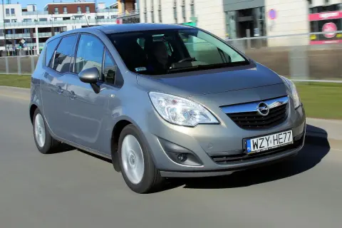 Szary Opel Meriva B w ruchu miejskim, z widocznym kierowcą za kierownicą.