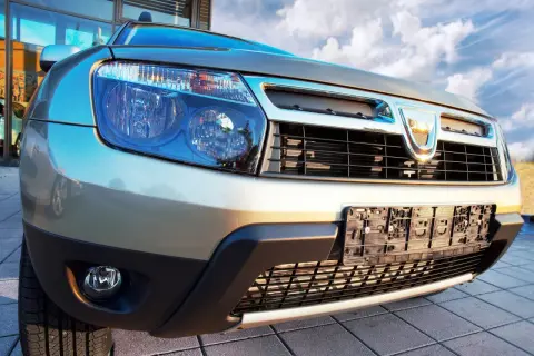 Złoty Dacia Duster 1.6 benzyna z bliska, z widocznym grillem i reflektorami.