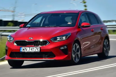 Czerwony Kia Ceed 1.4 benzyna w ruchu drogowym. Elegancki hatchback z dynamicznym wyglądem.