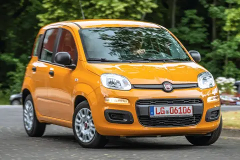 Pomarańczowy Fiat Panda 3 na drodze, z zielenią w tle.