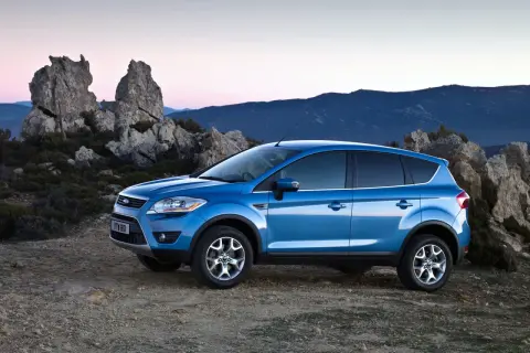 Niebieski Ford Kuga MK1 na tle skalistego krajobrazu o zachodzie słońca.