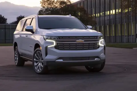 Biały Chevrolet Suburban zaparkowany przed nowoczesnym budynkiem.