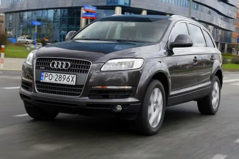 Ciemny Audi Q7 3.0 TDI w ruchu miejskim, z widocznym polskim numerem rejestracyjnym PO 2896X.