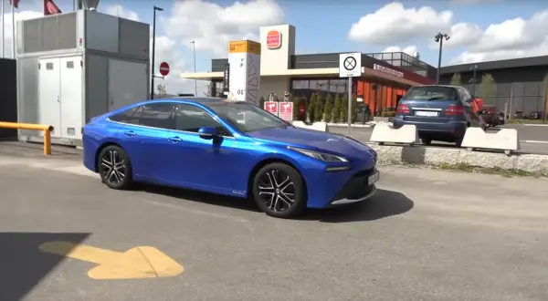 Niebieska Toyota Mirai, samochód wodorowy, parkuje obok stacji paliw. Sprawdzamy, jaka jest toyota mirai cena.