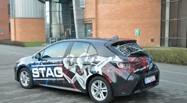Samochód hybrydowy z grafiką STAG, informującą o paliwie: cng i hybryda. Nowoczesny design podkreśla ekologiczny napęd.