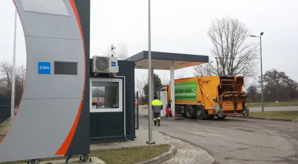 Stacja paliw z oznaczeniem CNG, gdzie można tankować gaz. Obok żółta śmieciarka z napisem "System Eko".