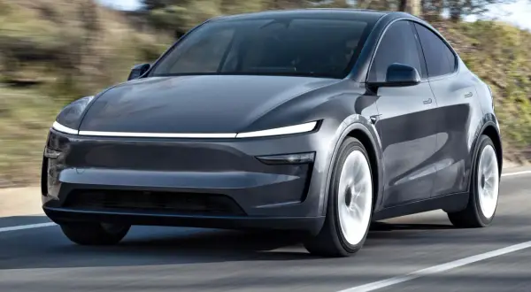 Szary Tesla SUV pędzi po drodze, otoczony rozmytym krajobrazem.