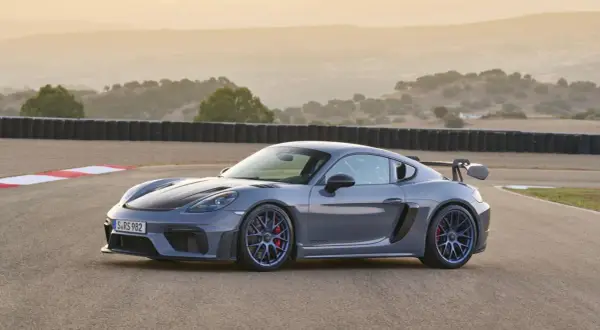 Szary Porsche GT4 RS na torze wyścigowym, z charakterystycznym skrzydłem i niebieskimi felgami.