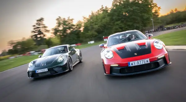 Dwa Porsche GT3, czerwone i zielone, ścigają się na torze wyścigowym.